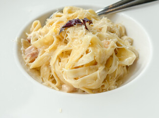 gourmet pasta dish, creamy fettuccine alfredo with grated cheese and a small garnish