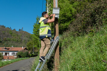 Técnico de telecomunicações em cima de uma escada a realizar reparo numa caixa de distribuição...