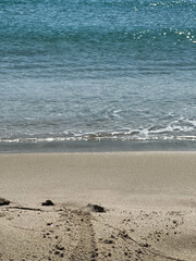 beach scenery, a serene beach with gentle waves gently touches the shore, reflecting the suns sparkle on the water pebbles and tracks dot the sand