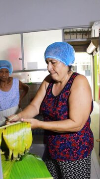 A latina woman cutting a plantain leaf to prepare Quesillo inside a kitchen in Yaguara, Huila, Colombia. Colombian food concept