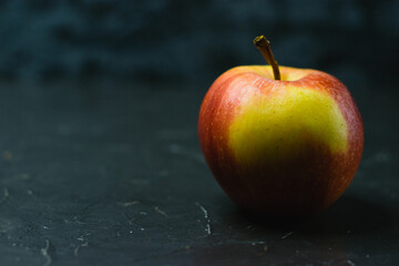 Bright yellow red apple on dark concrete background with space for text. Healthy eating concept