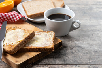 Sliced fresh bread with butter and coffee for breakfast on wooden table. Copy space