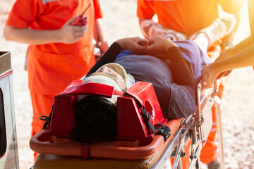 Paramedic, emergency, ambulance staff and medical help. Ambulance staff member assisting injured person with transport stretcher. Paramedics assisting injured person first aid on road