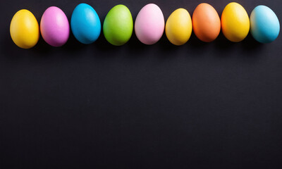 Brightly colored eggs arranged in a line on a dark surface for an Easter celebration