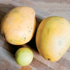 A fresh display of two ripe Badami mangoes alongside a lemon, perfect for a tropical and tangy summer delight.