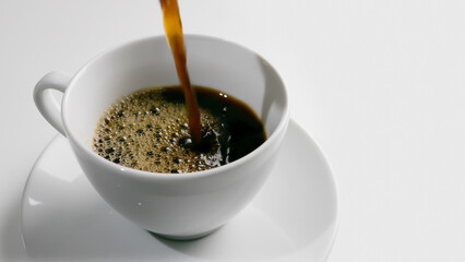 pouring coffee into a white cup isolated on white background, closeup and high angle view