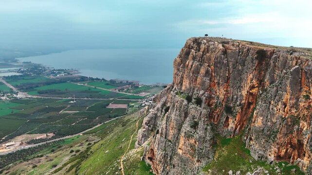 Aerial view of Mount Arbel overlooking the Sea of Galilee. Captured by drone, this breathtaking landscape showcases the dramatic cliffs of Arbel, lush valleys, and the sparkling waters of Lake Kinnere