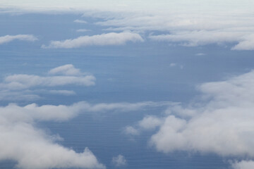 A beautiful scene of fluffy clouds floating above the water. The soft clouds contrast against the calm sea, creating a peaceful and serene atmosphere.