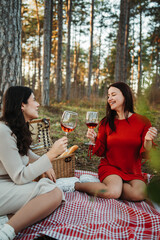 Two young caucasian woman have picnic drink wine in the forest	
