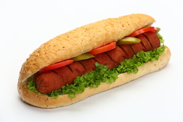 Sesame seed bun hot dog with sausage, lettuce, tomato slices, and pickles on a white background