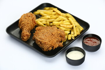 Crispy fried chicken pieces and french fries on a black plate with various dipping sauces on white
