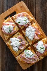 Pinsa Romana with mortadella, burrata cheese and pistachio on wooden table	