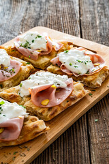 Pinsa Romana with mortadella, burrata cheese and pistachio on wooden table	