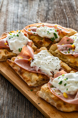 Pinsa Romana with mortadella, burrata cheese and pistachio on wooden table	