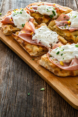 Pinsa Romana with mortadella, burrata cheese and pistachio on wooden table	