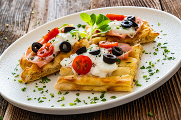 Pinsa Romana with mortadella, burrata cheese, black olives and cherry tomatoes on wooden table	