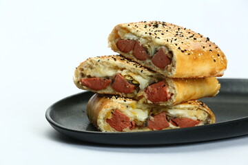 Stacked, sliced Stromboli on black plate: filled with meat and/or sausage and cheese on white
