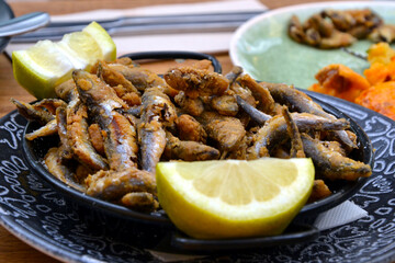 Deep fried sardines with fresh lemon on a plate. Crispy fried sardines with herbs and lemon. Mediterranean food