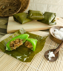 This photo shows jajanan mendut, a traditional Indonesian snack made from sticky rice flour and coconut. in the center is brown sugar and sweetened coconut. The snack is usually served on banana leave