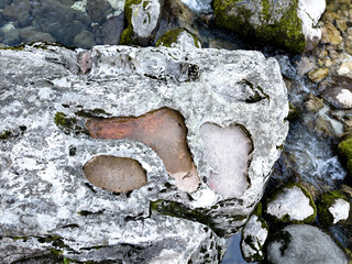 natural stone with organic shaped erosion hole above running stream. unique detailed rock texture. abstract nature background. eco, geology or