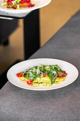 A beautifully plated omelet garnished with fresh herbs and cherry tomatoes rests on a table. The elegant presentation invites a delightful dining experience in a cozy setting.