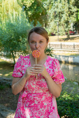 Fototapeta premium Pretty blonde girl wearing pink and white dress in the park 