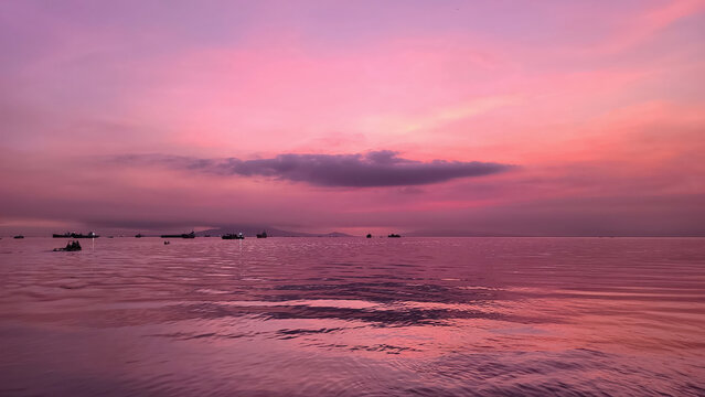 Cloudy Afternoon on C4 Navotas: Pink and Purple Hues Reflecting on the Ocean with Boats Silhouetted Against a Tranquil Horizon.