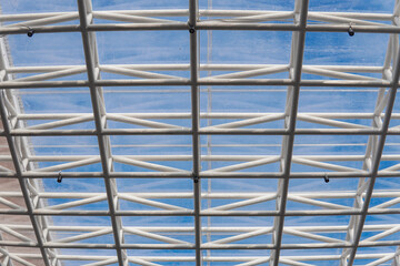 Glass roof with blue sky and clouds. Modern panoramic glass roof with many metal cell sections