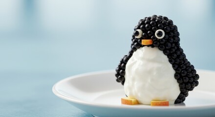 Cute dessert creation resembling a penguin made from blackberries and cream cheese served on a white plate at a cozy kitchen