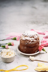 Easter Easter cake, Easter bread with cottage cheese, sprinkled with powdered sugar on a light background, next to Easter eggs, yellow ribbon, rag doll Easter bunny