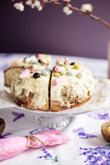 Easter cinnabon with buttercream, marshmallows, nuts on a glass cake plate, flowers on a rack. Easter bread. Easter concept.