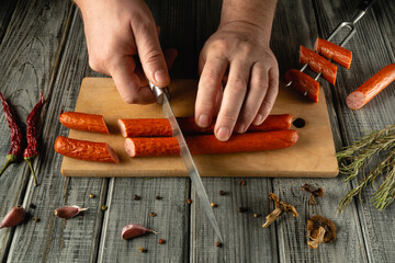 Hands expertly slice spicy sausages on a wooden cutting board, surrounded by herbs and spices. The warm, rustic kitchen atmosphere enhances the culinary experience