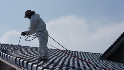 Two men painting a roof of a house .