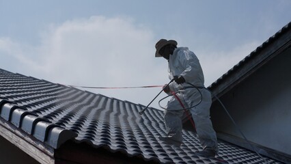 Two men painting a roof of a house .