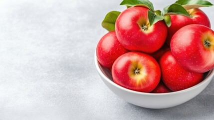 Fresh red apples in a white bowl.  Crisp, juicy, and vibrant red apples sit in a simple white bowl, showcasing their plumpness.  Green leaves add a touch of nature