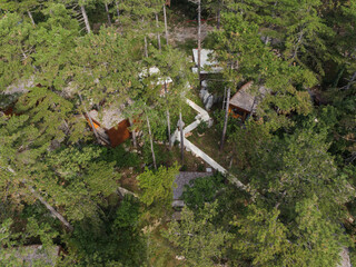 Aerial view of glamping hut with wooden deck and hot tub in forest. Drone shot