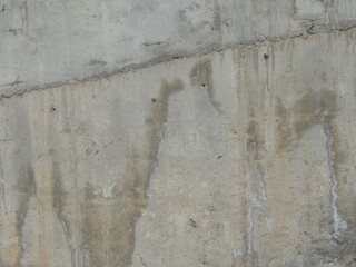 old concrete wall with cracks and stains as rough urban background, cement broken shattered texture...