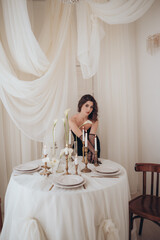 Woman in black dress sitting at a festive table with candles and flowers