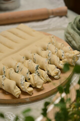 Close up twisted dough strips on wooden board. Green towel, rolling pin, microgreens on kitchen table. Home cooking baking puffs