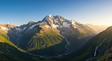 Majestic mountain landscape during sunset with snow-capped peaks and lush green valleys in the distant wilderness