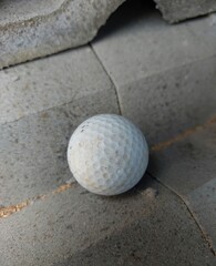 Golf ball resting on a textured brick surface, contrasting sports equipment with rough background. Ideal for creative concepts, sports themes, and unique compositions