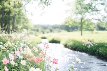 Fototapeta premium Tranquil stream flowing through meadow of colorful wildflowers in sunlight