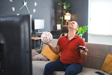 Middle age Caucasian man playing soccer video game at home
