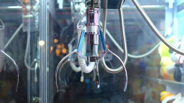 A claw machine with a claw grabbing a toy
