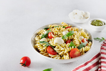 Italian salad with pasta and fresh vegetable cherry tomatoes, mozzarella, arugula on a white background
