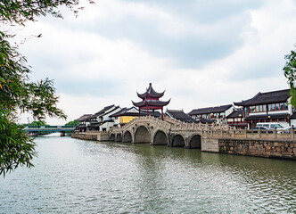 Fototapeta premium Scenic view of a traditional bridge and architecture alongside a tranquil river in a historic Chinese town