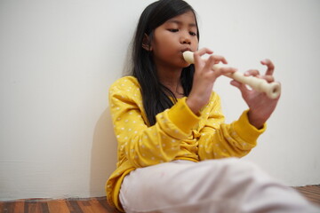 Fototapeta premium Asian girl playing recorder flute, musical instrument