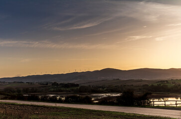 The lake of Santa Luce in the Tuscan countryside during a colorful sunrise with the typical landscape of hills and trees