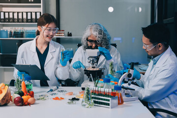 Team Asian scientists in a lab conducting food research using a microscope and lab equipment,...