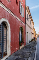 An old man on the sidewalk of the  narrow streets in the medieval town of Riparbella in Tuscany